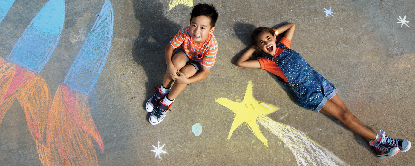 two young kids lying on the sidewalk with chalk drawings