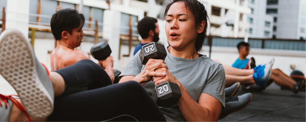 Woman holding a 20lb weight performing a sit-up