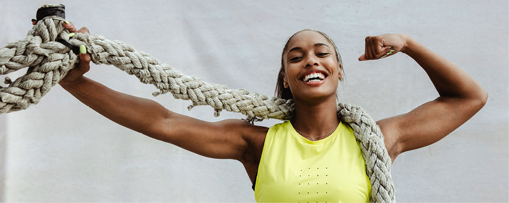 Woman flexing bicep and holding a rope with a big smile