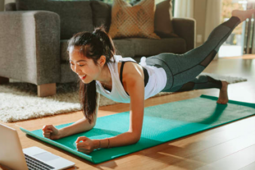 woman doing yoga in front of her laptop