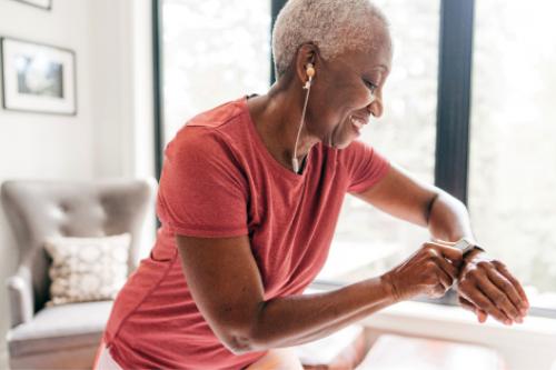 Tech savvy senior with headphones checking her fitbit watch