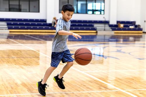 happy kid dribbling basketball