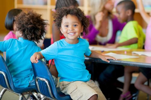 small kids sitting around a table smiling