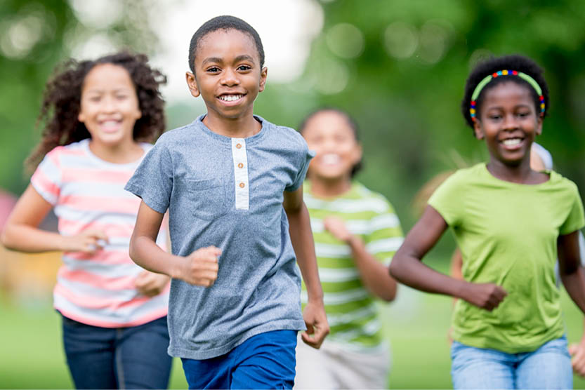 four elementary students running outside