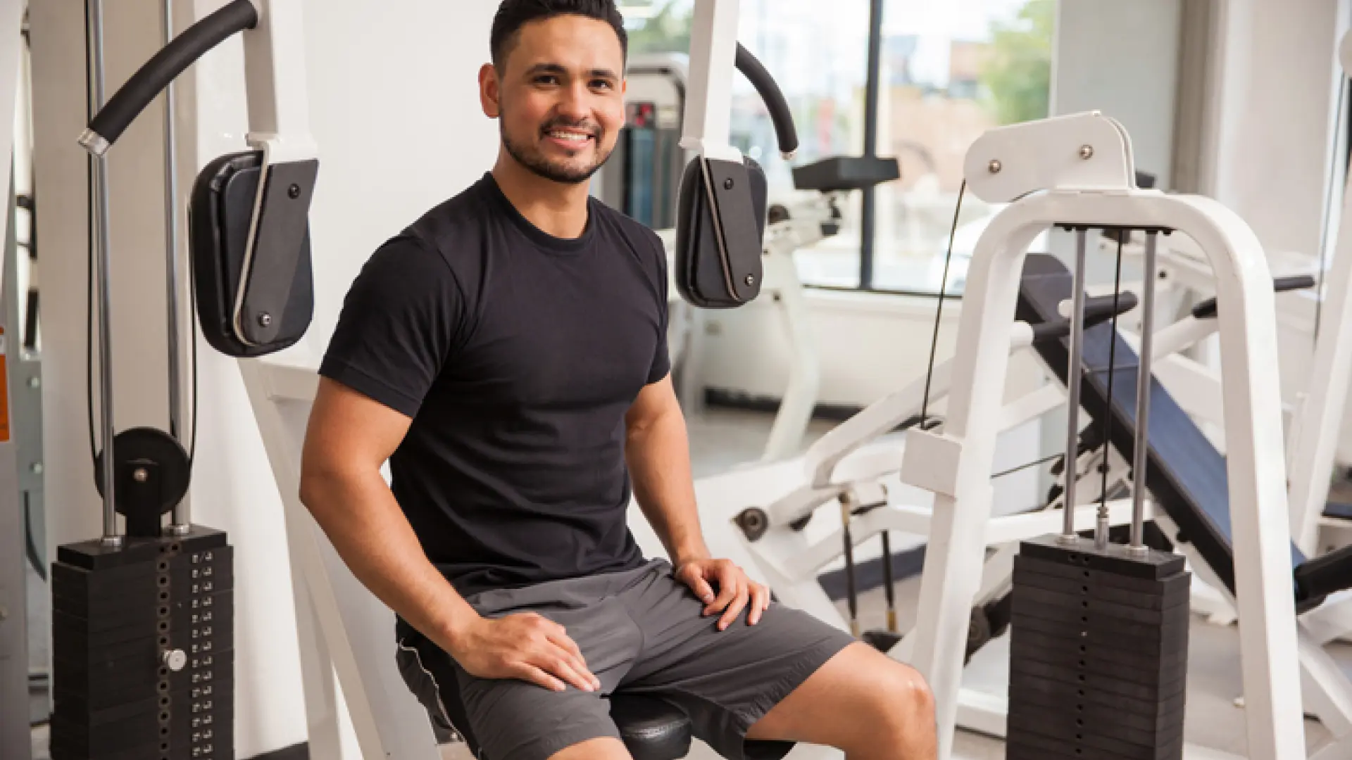 Younger man sitting on circuit machine and smiling at the camera