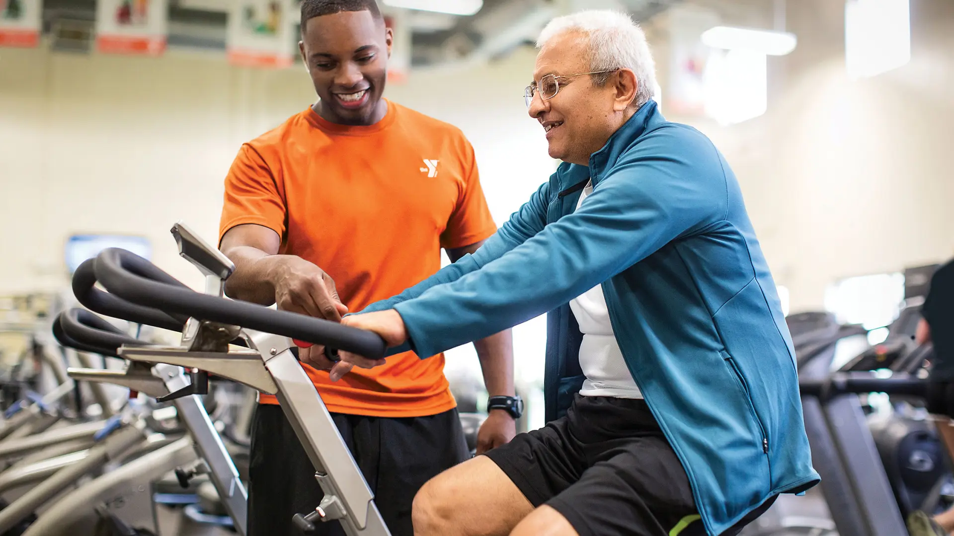 YMCA male staff giving instruction to senior adult male member