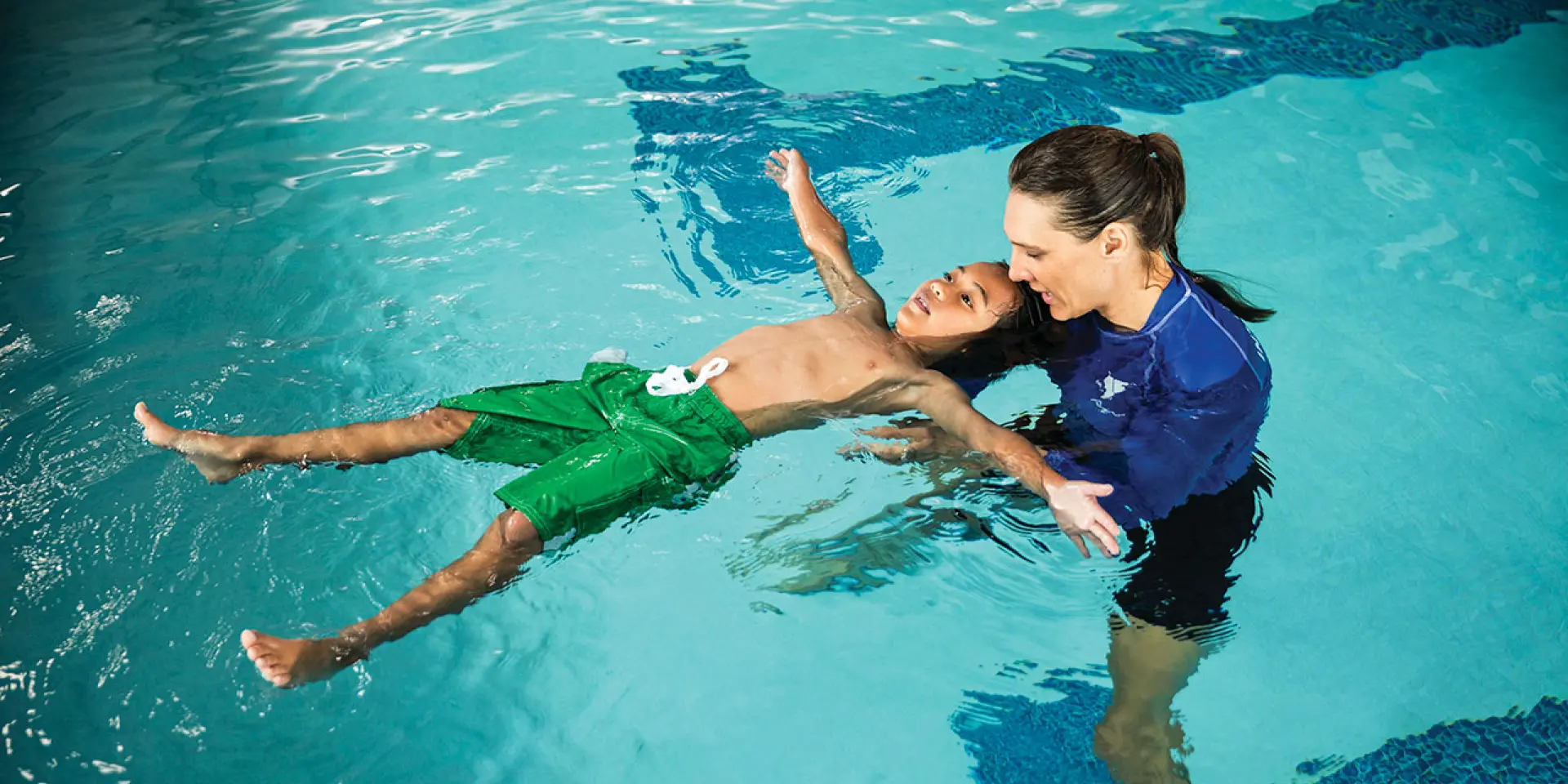 swim lesson for school age male student in an indoor pool