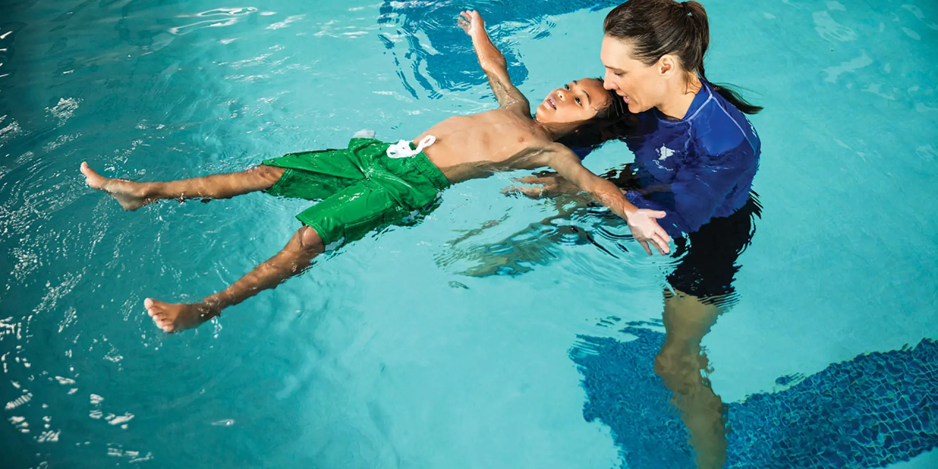 swim lesson for school age male student in an indoor pool