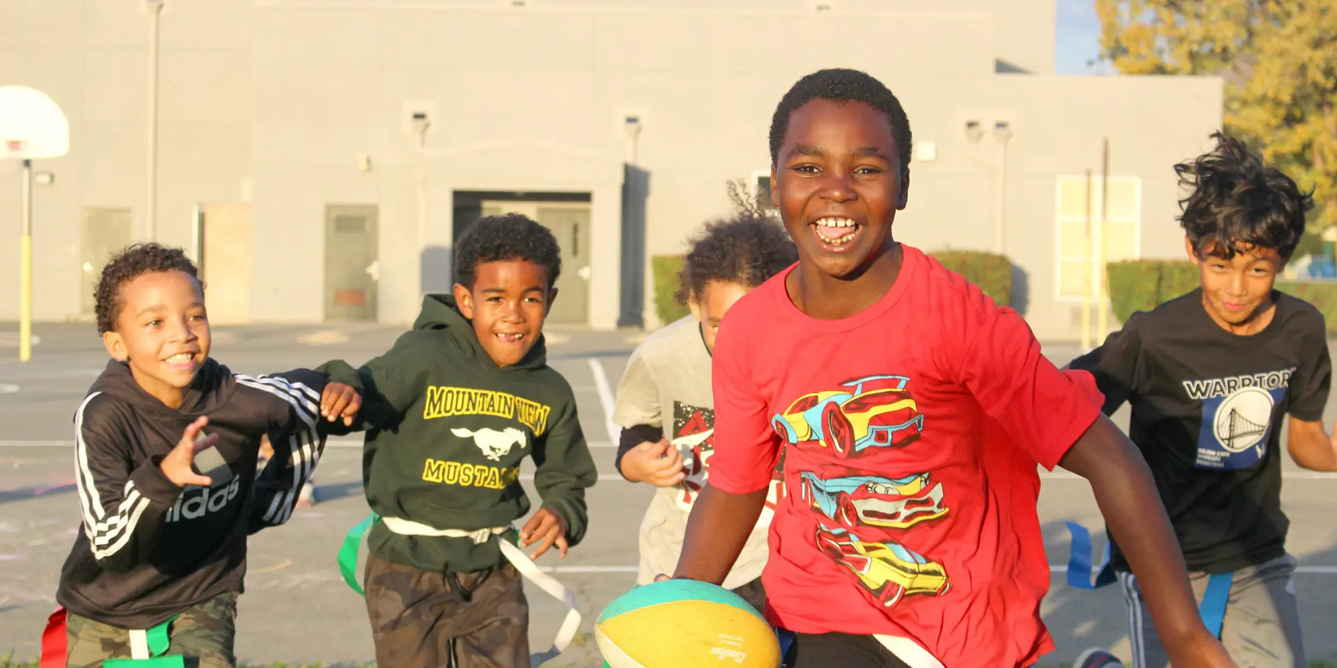 Young students running and playing catch with football