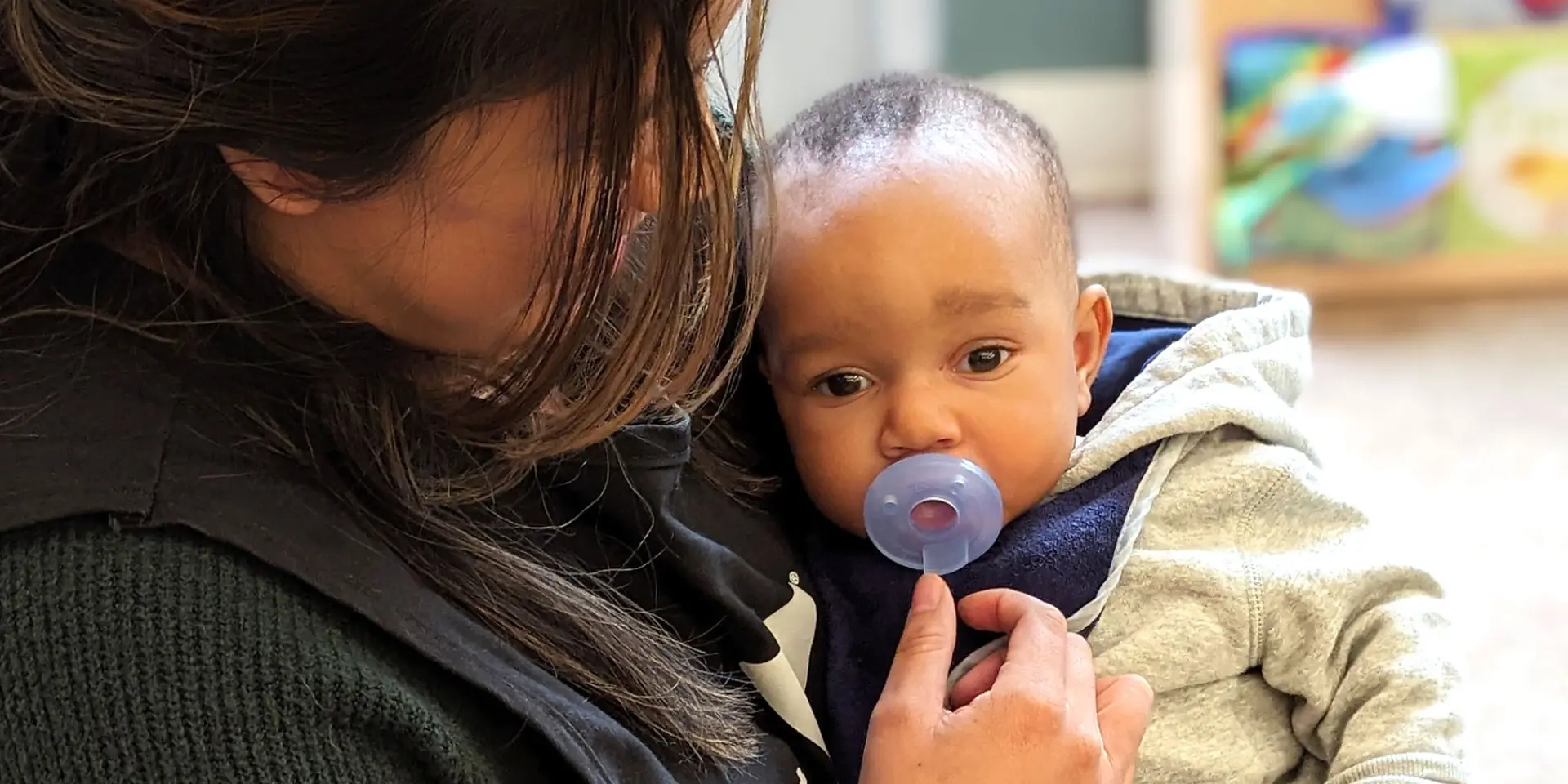 Infant being held and soothed by preschool teacher