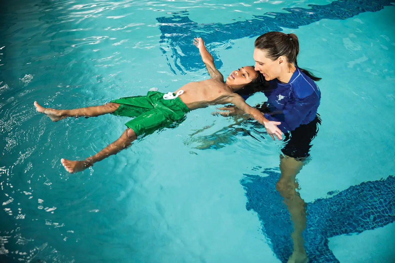 swim lesson for school age male student in an indoor pool