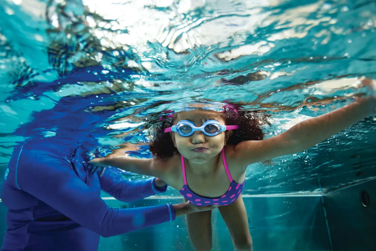 young female under water taking a swim lesson from YMCA aquatics instructor in an indoor pool