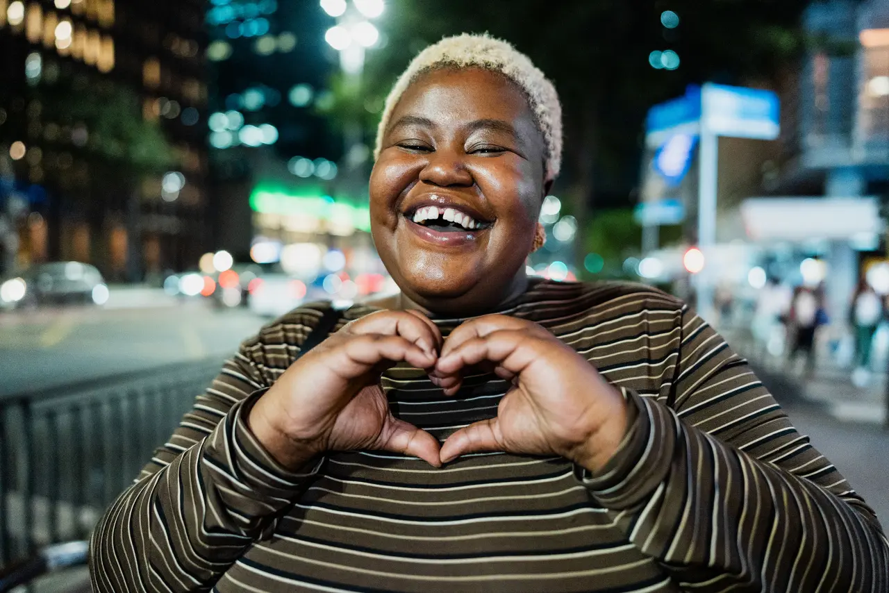 Young female smiling while making a heart with her hands