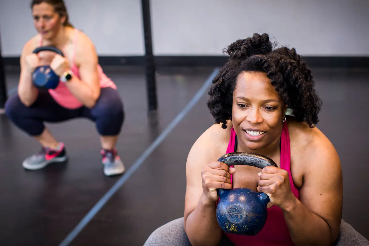 adult woman holding kettlebell in group exercise class