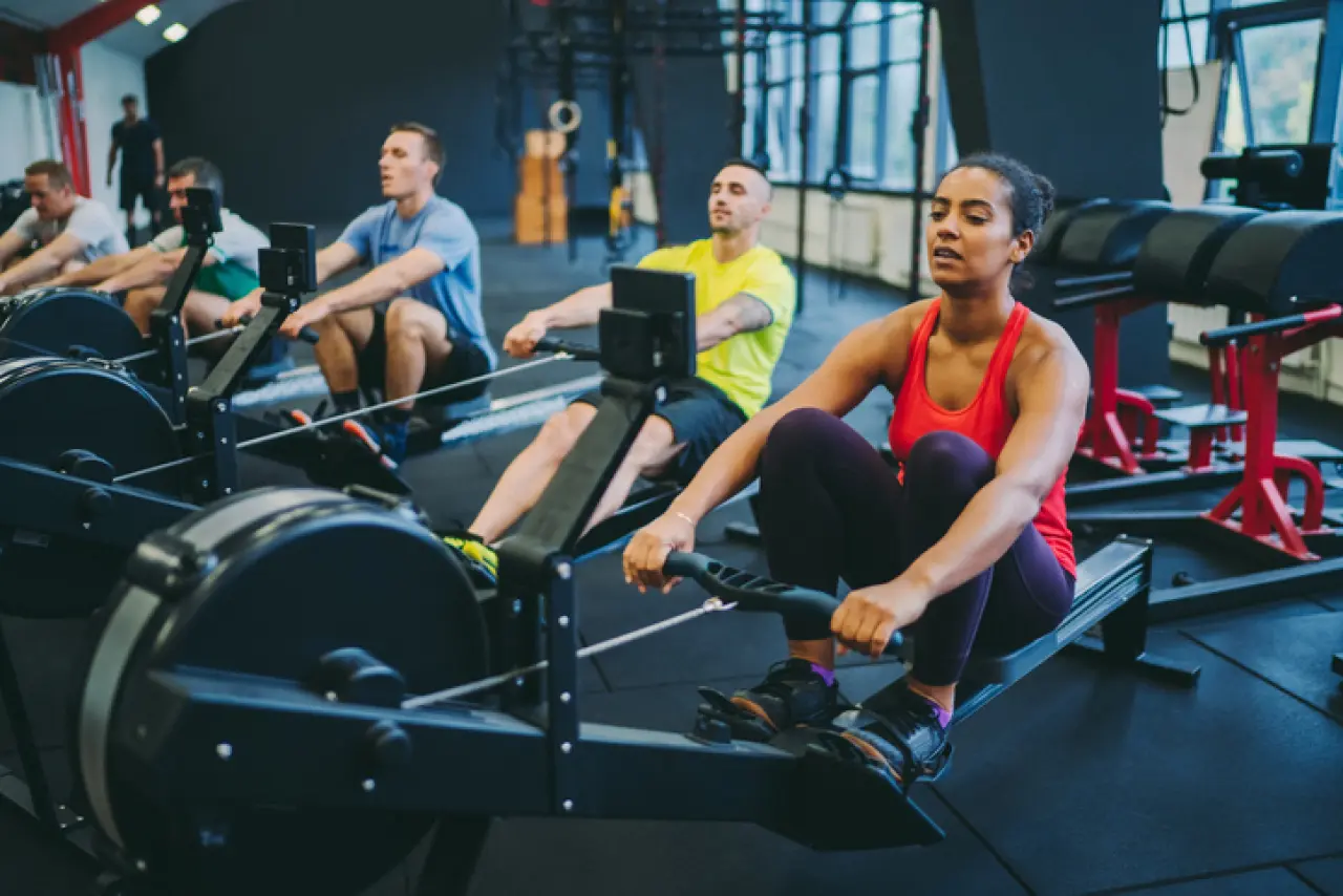Group of three people exercising on rowing machines