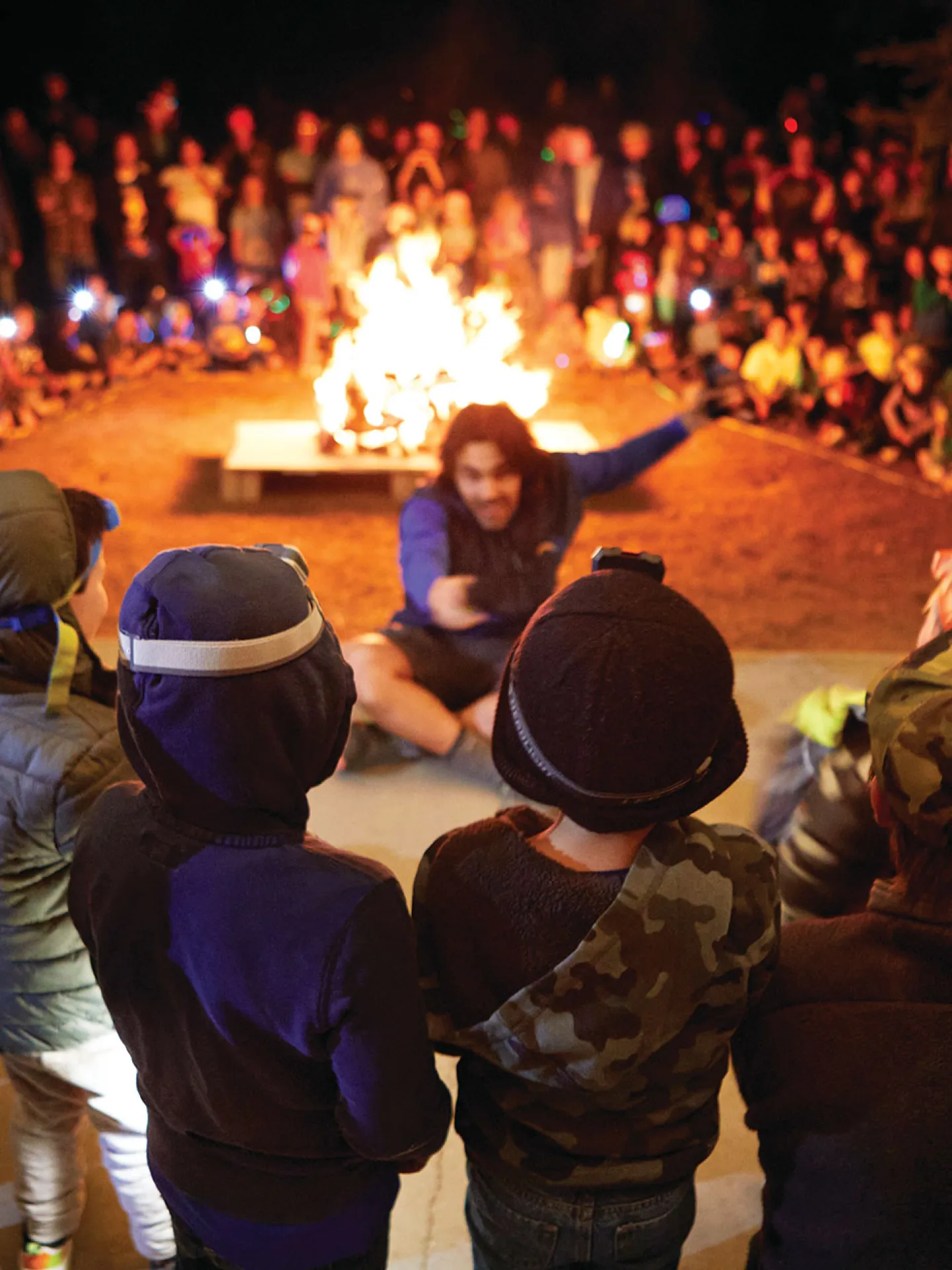 Camp Loma Mar counselor telling a story at night to a group of campers around the fire pit