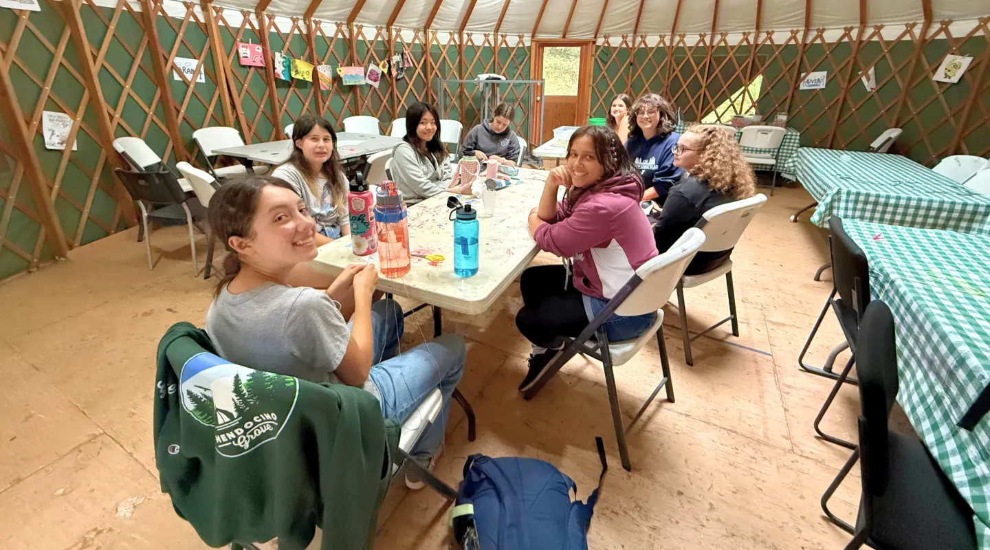 Camp Loma Mar campers sit at a table in the arts and crafts yurt with their counselor.