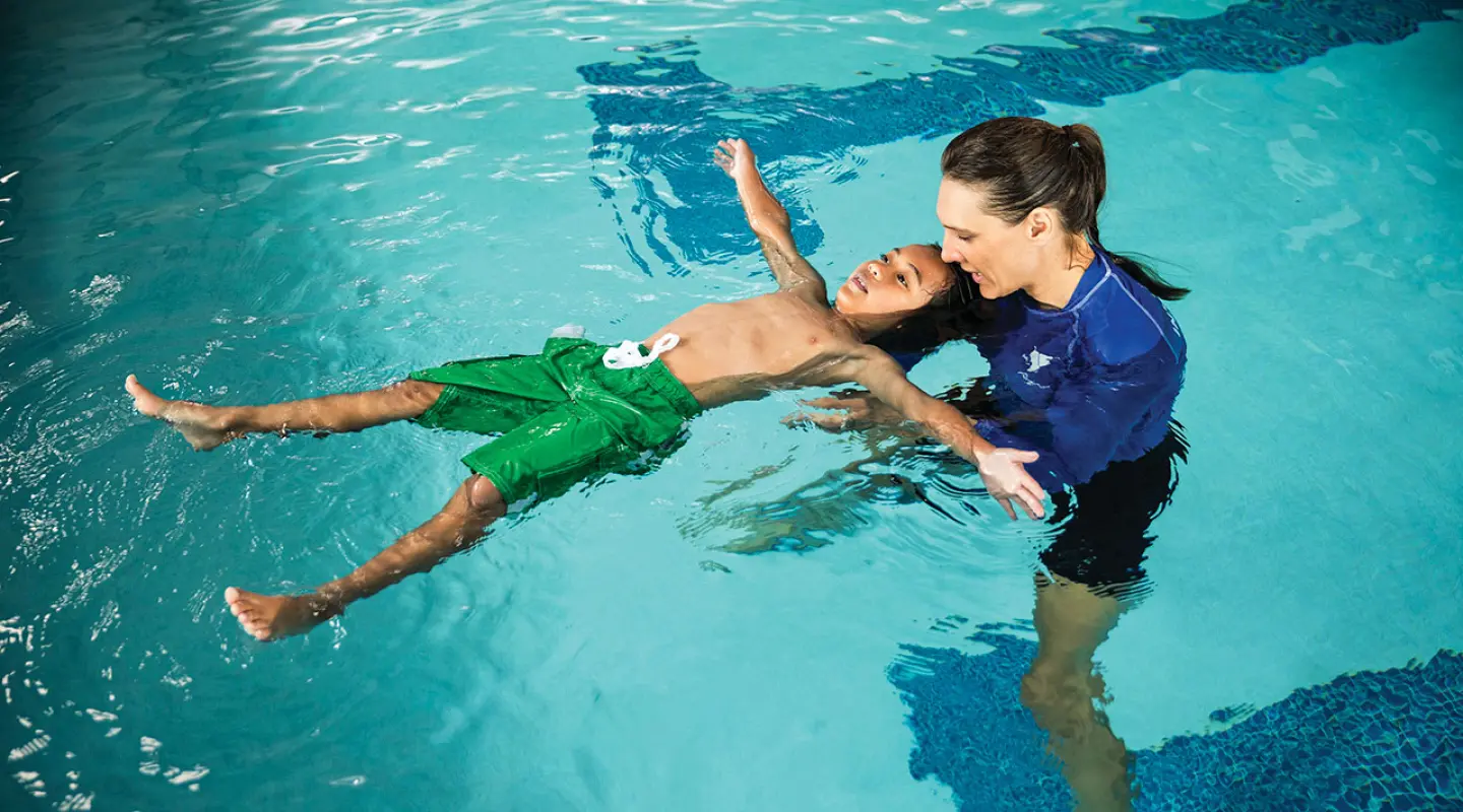 swim lesson for school age male student in an indoor pool