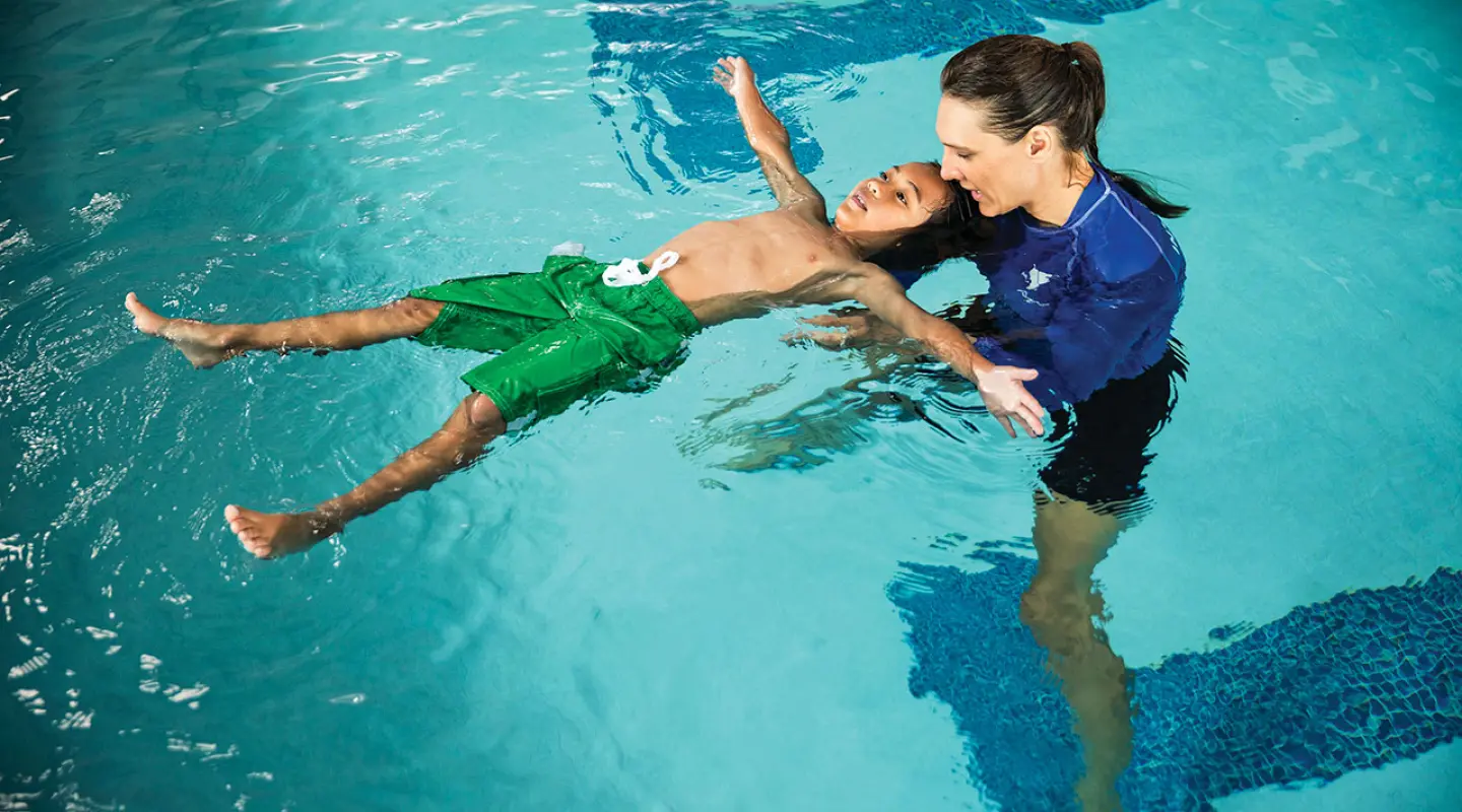 swim lesson for school age male student in an indoor pool