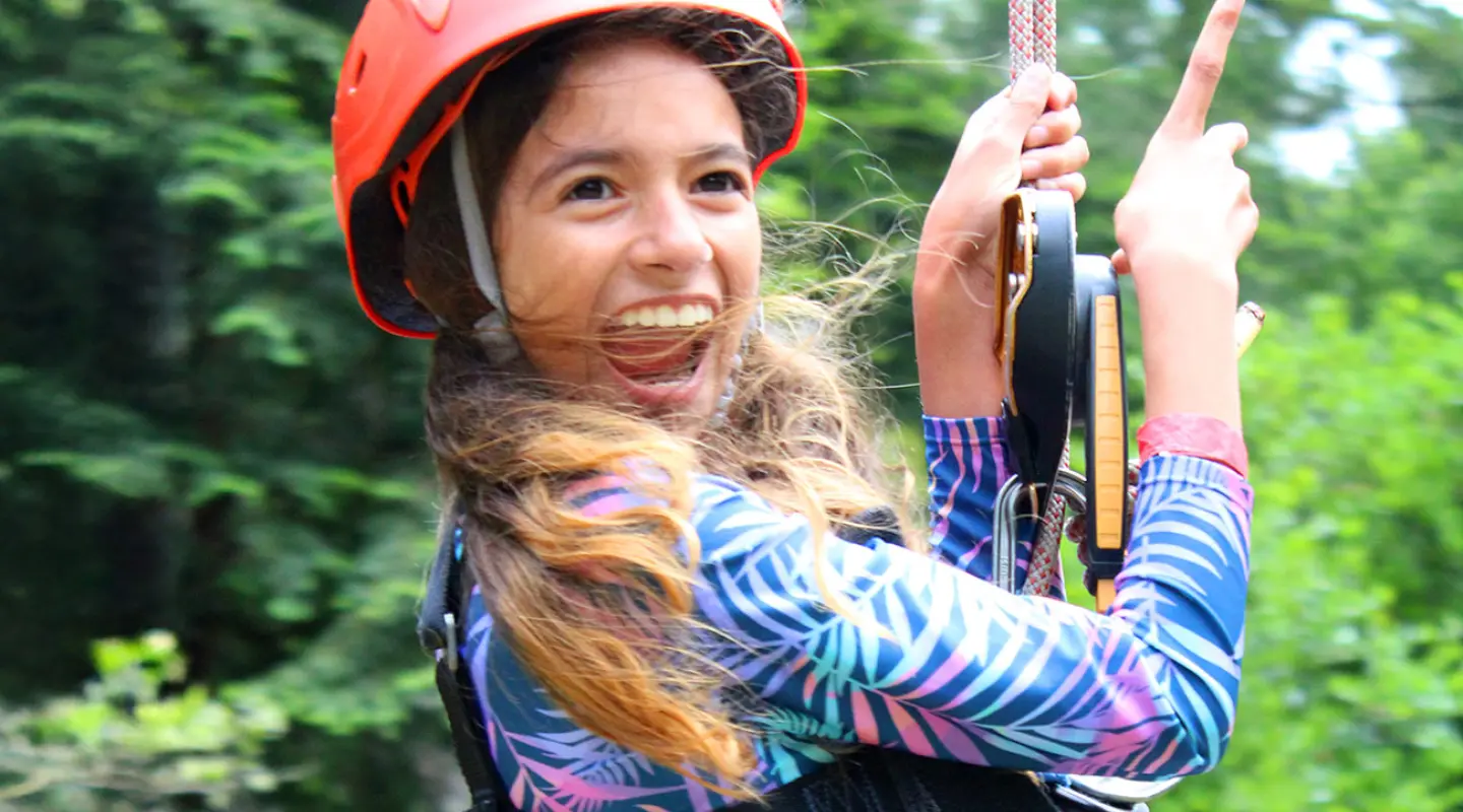 Camp Loma Mar female camper smiling while on the zip line