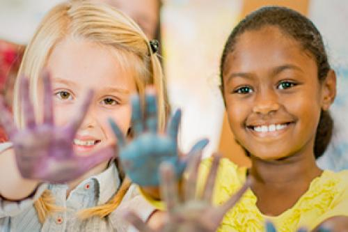 Two girls smiling and doing hand painting