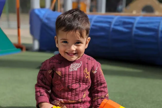 Early Learning Center male toddler playing with blocks on outdoor playground