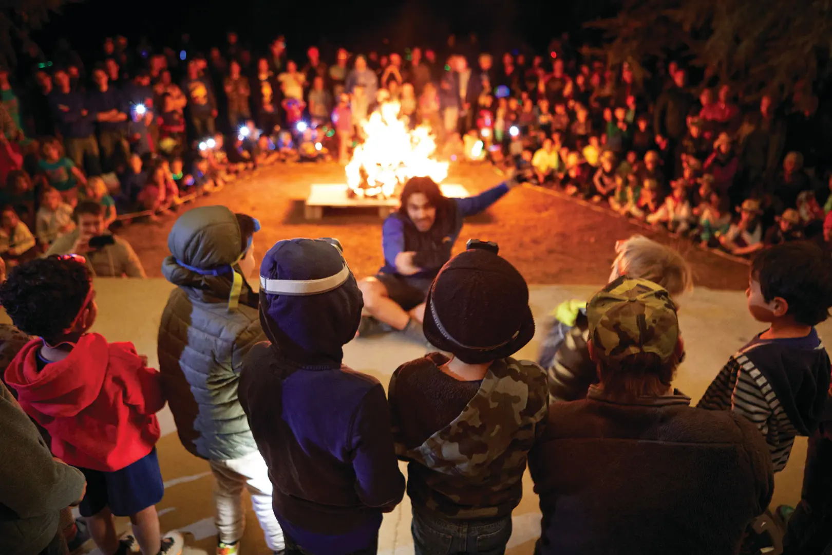 Camp Loma Mar counselor telling a story at night to a group of campers around the fire pit