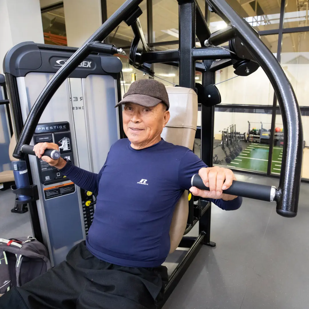Adult male senior working out arms on one of the weight machines