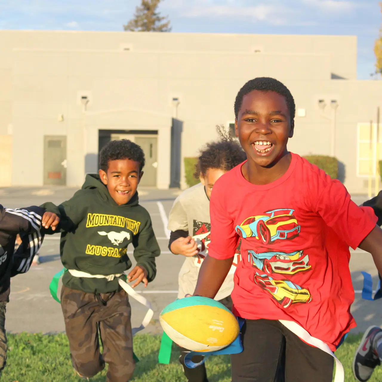 Young students running and playing catch with football