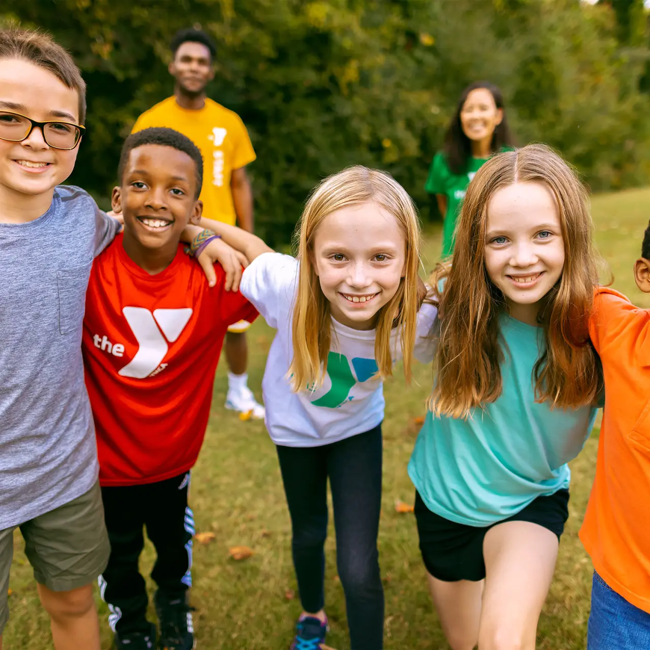 Group of school age smiling children with YMCA staff outdoors
