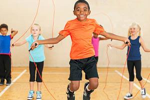 Children jumping rope in gym.