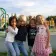 Group of young students smiling with arms around each other in front of outdoor playground structure 