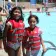 smiling young female campers in front of pool with life vests on