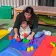 YMCA Cherryland Early Learning Center teacher with a small infant playing with blocks on the outdoor playground