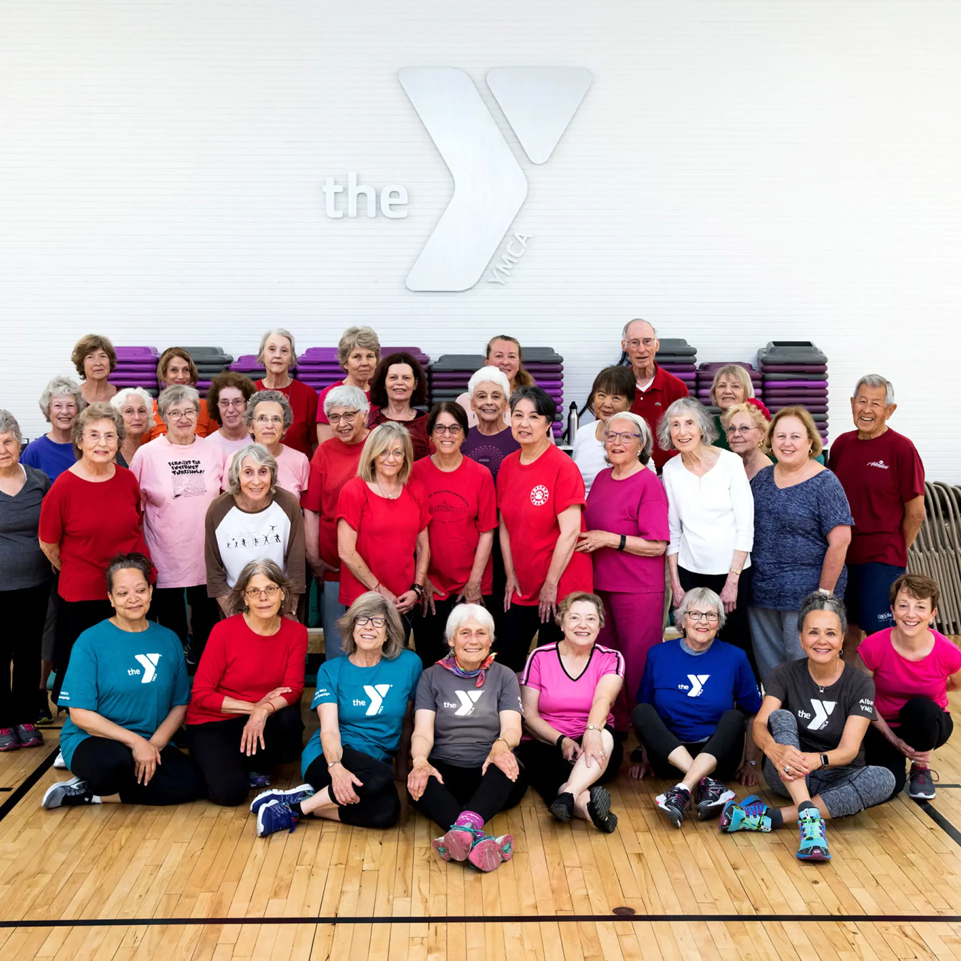 Group of Albany YMCA members after a group exercise class in the gym under the Y logo