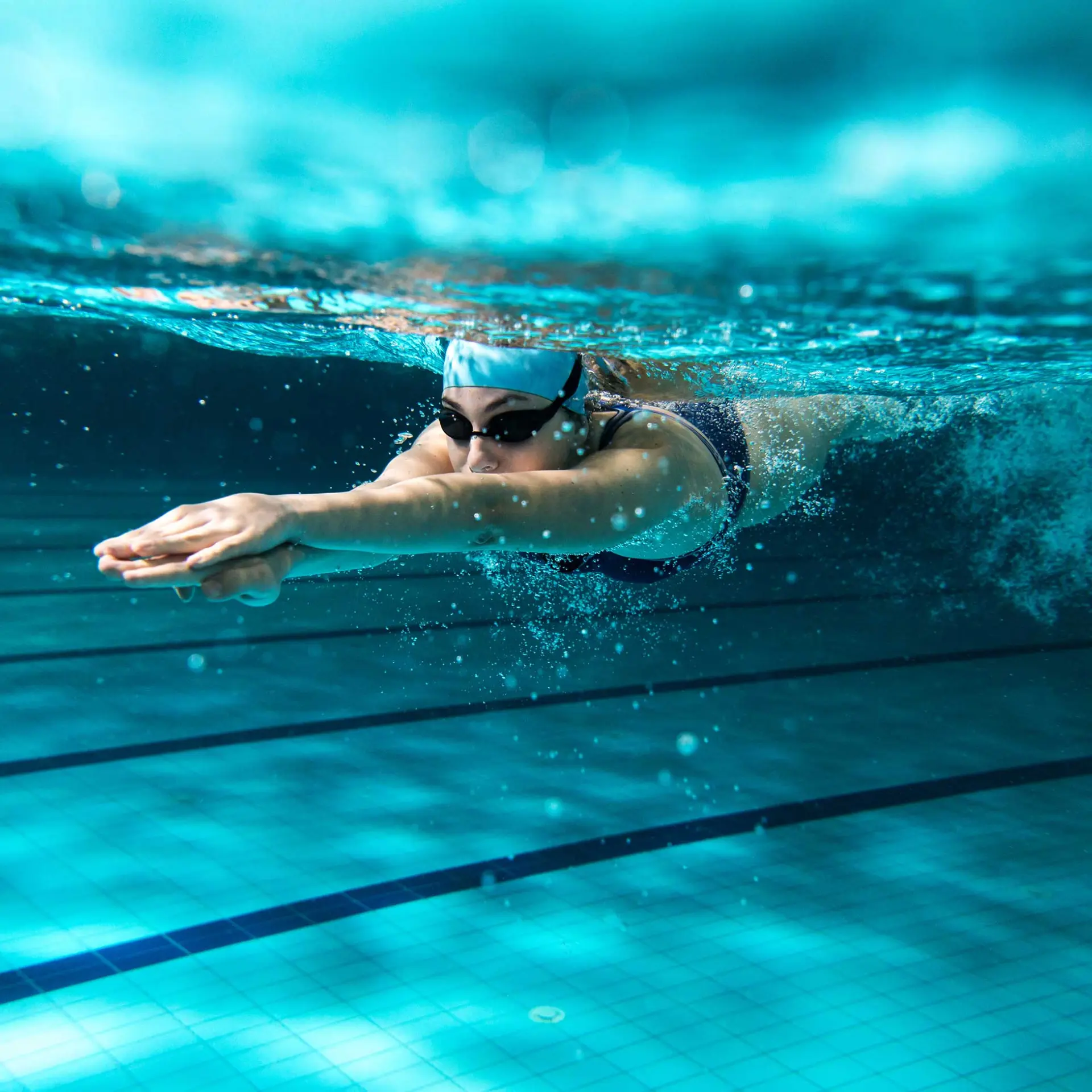 adult female doing underwater laps in indoor pool