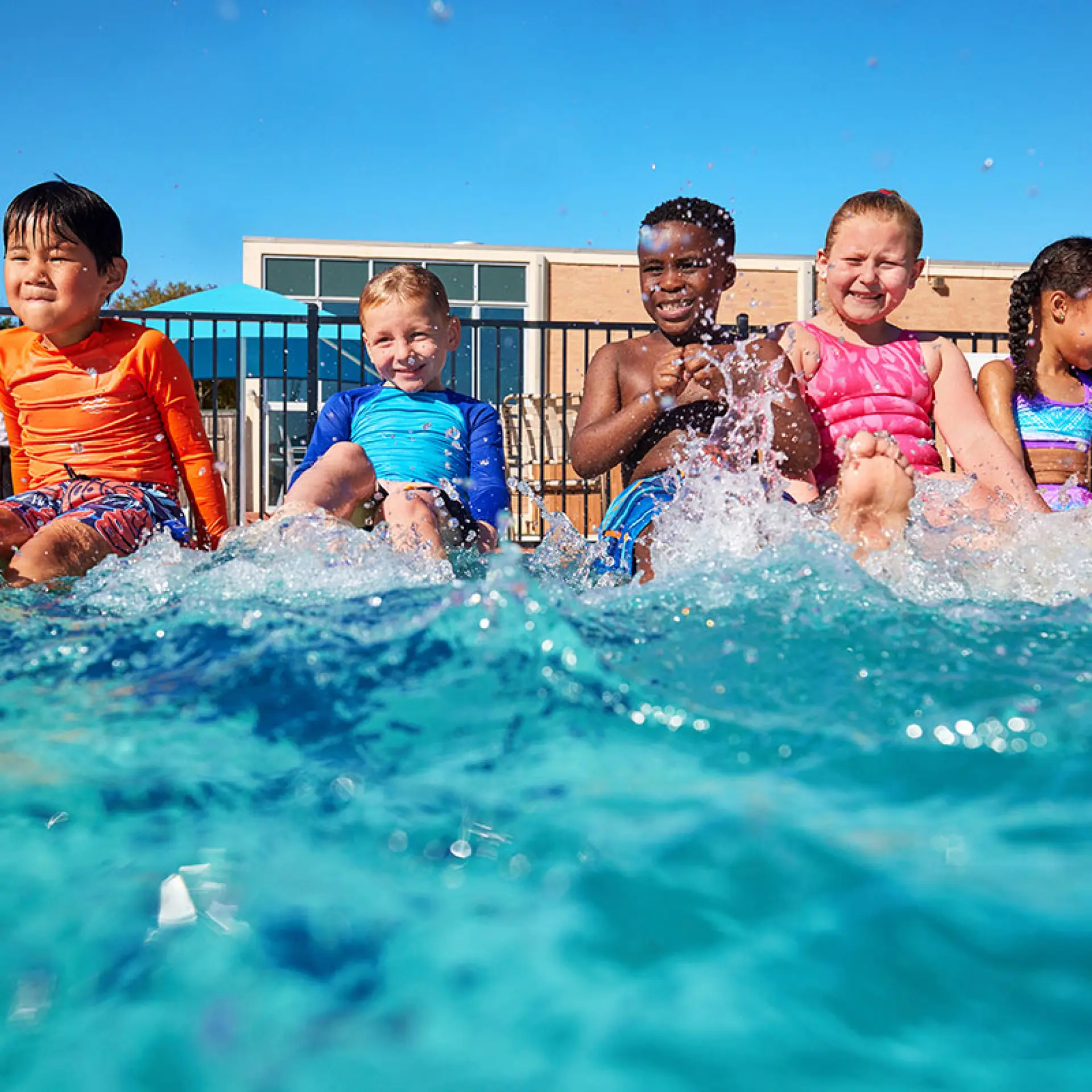 diverse group of school age children in outdoor swimming pool