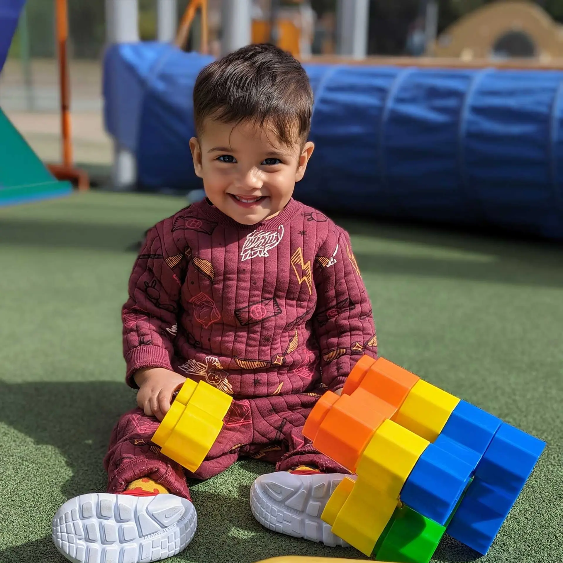 Early Learning Center male toddler playing with blocks on outdoor playground