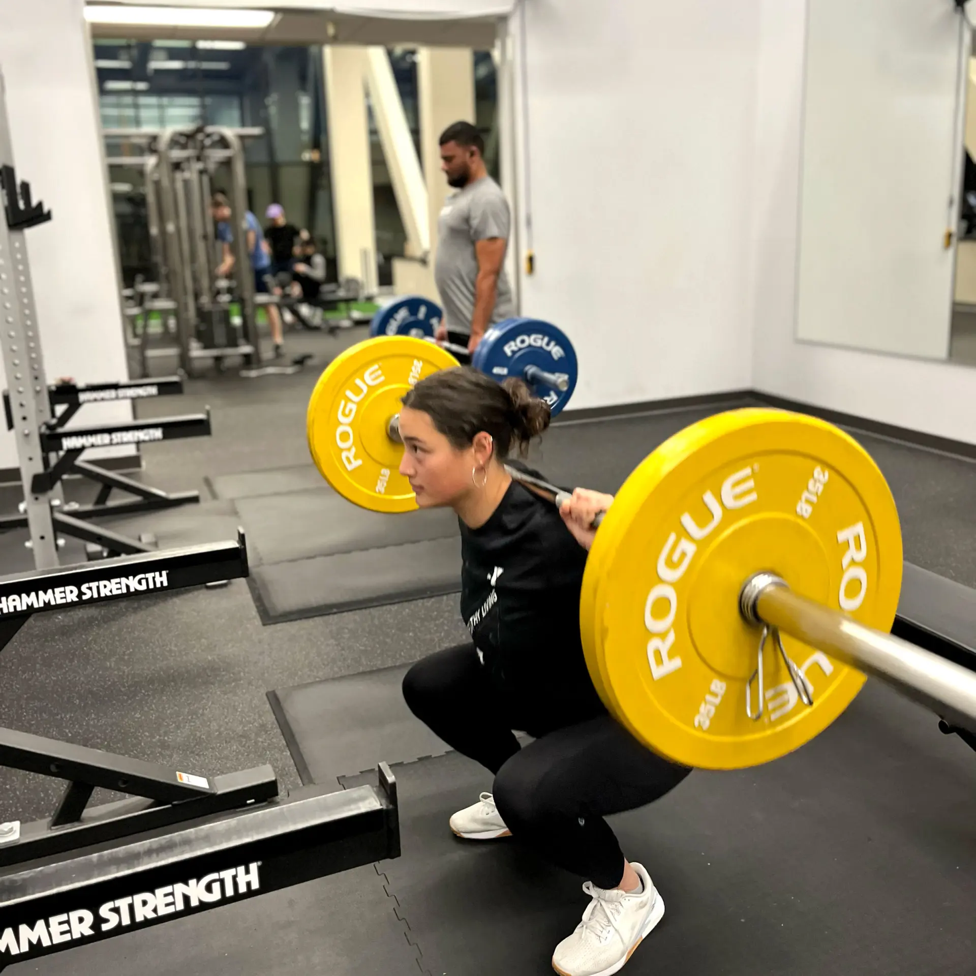 Young adult woman lifting barbell in weights area of the Oakland YMCA