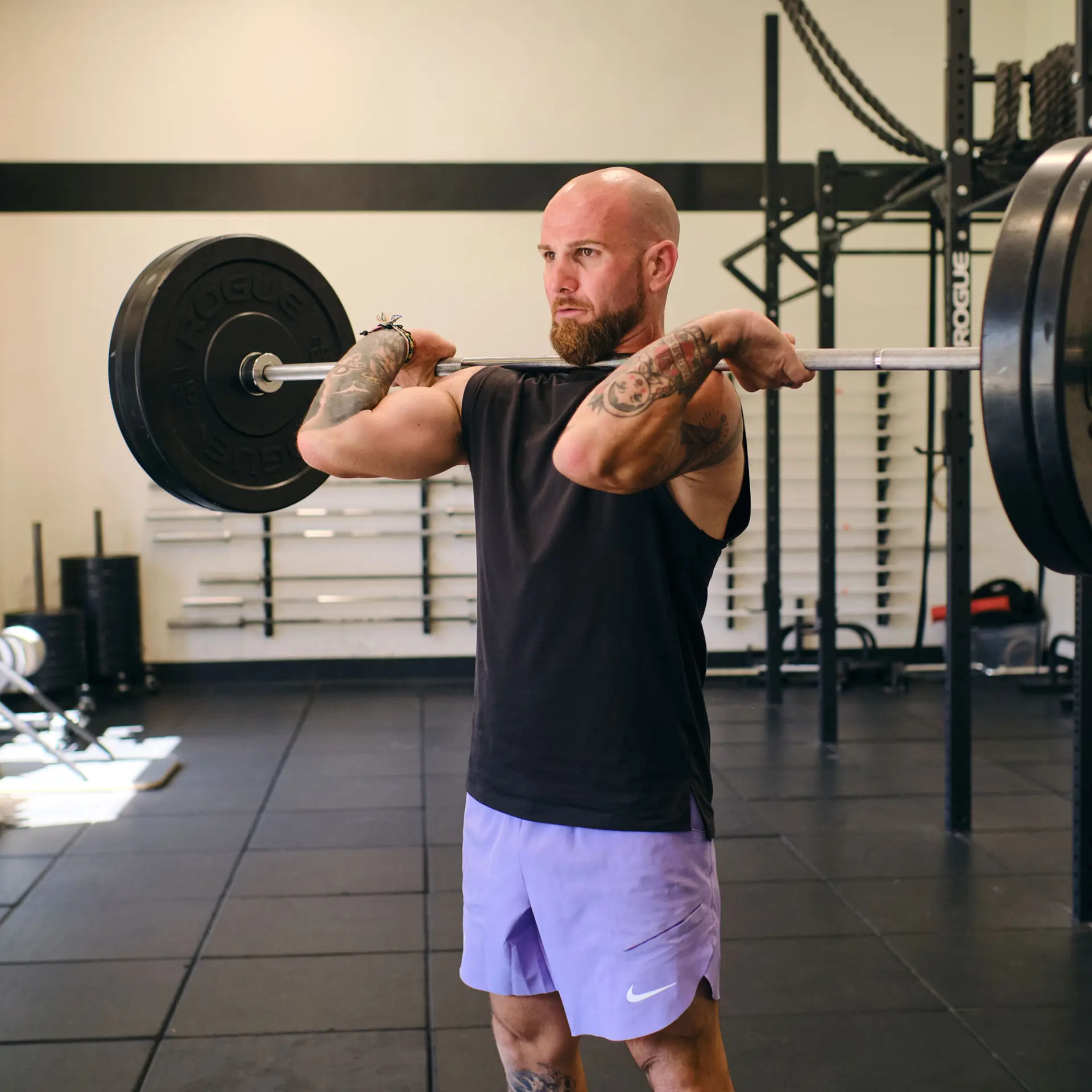 Senior Fitness Director holding barbell in front rack position