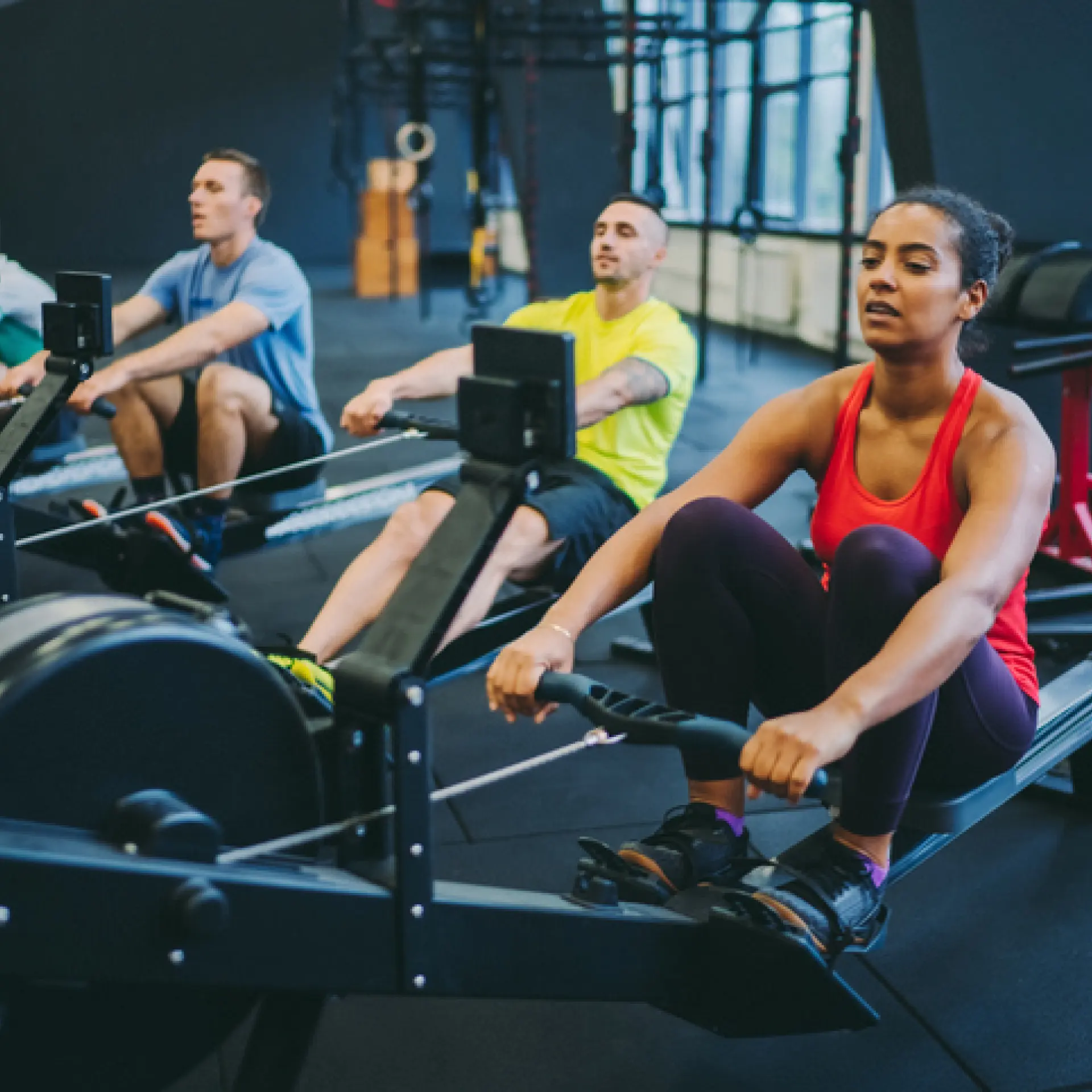 Group of three people exercising on rowing machines