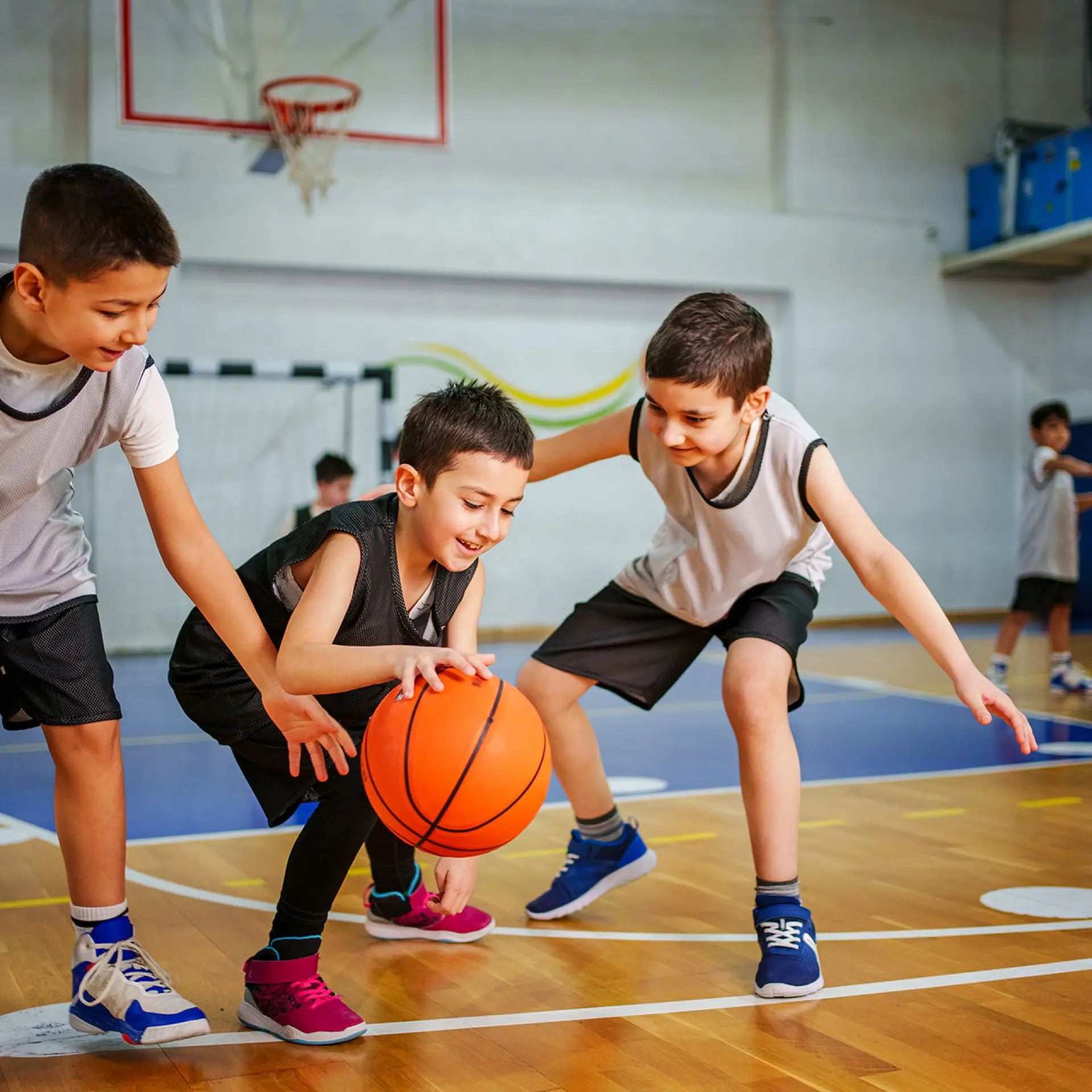 group of young student age males playing basketball on indoor court