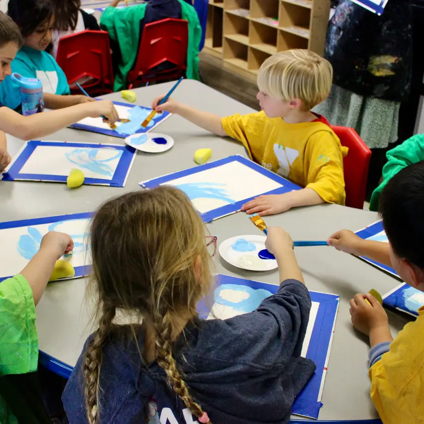 Group of young students working on art projects at indoor work table