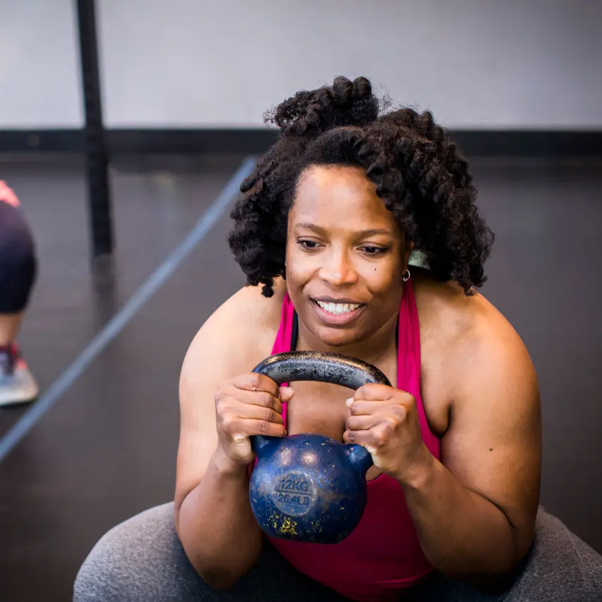 adult woman holding kettlebell in group exercise class
